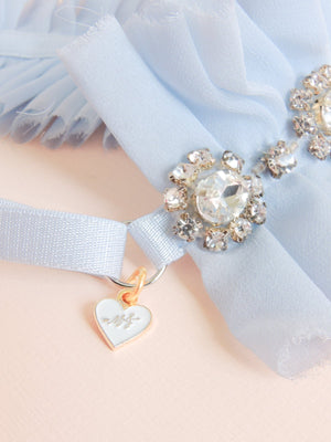 Close up detail of Alexandra silk chiffon wedding garter with rhinestone banding and gold plated mamie + james charm